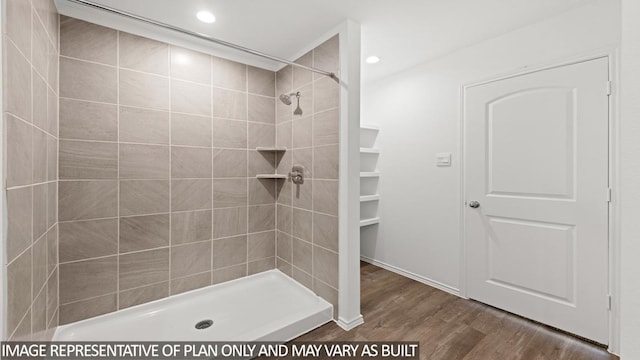 bathroom with tiled shower and hardwood / wood-style flooring