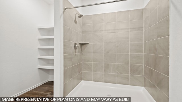 bathroom featuring hardwood / wood-style floors and a tile shower