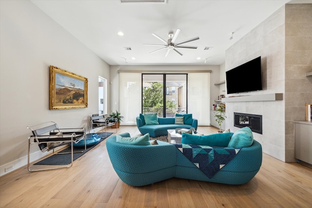 living room with ceiling fan, a tile fireplace, and hardwood / wood-style floors