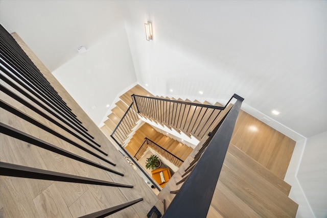 stairs with wooden walls, wood-type flooring, and a towering ceiling