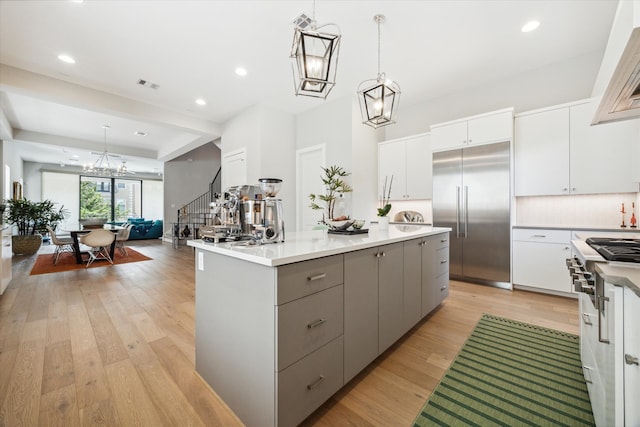 kitchen featuring white cabinets, hanging light fixtures, and built in refrigerator