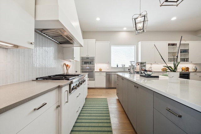 kitchen featuring white cabinetry, premium range hood, gray cabinetry, and hanging light fixtures