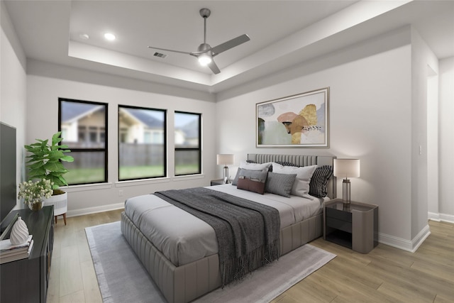 bedroom featuring ceiling fan, light hardwood / wood-style flooring, and a tray ceiling