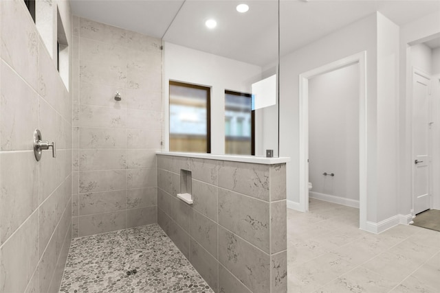 bathroom featuring tiled shower and toilet