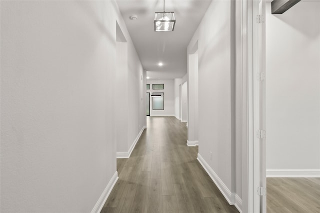 hall with wood-type flooring and an inviting chandelier