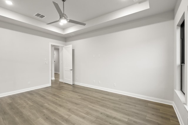 unfurnished room with a tray ceiling, ceiling fan, and hardwood / wood-style floors