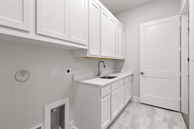 laundry room with electric dryer hookup, cabinets, and sink