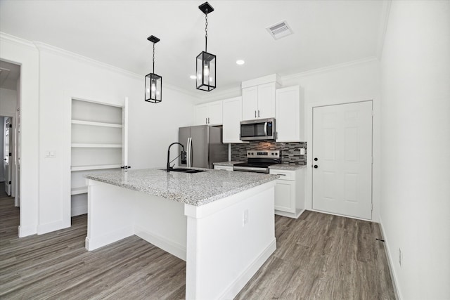 kitchen featuring light hardwood / wood-style flooring, stainless steel appliances, a center island with sink, decorative light fixtures, and white cabinets