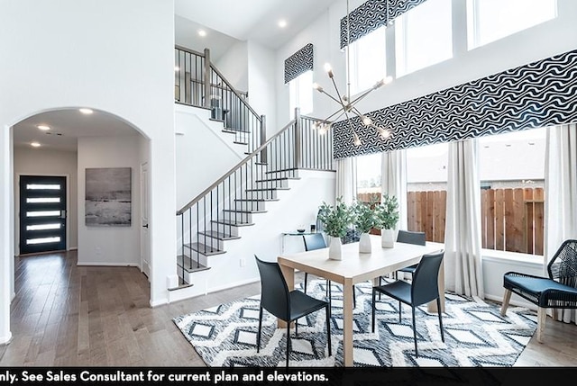 dining space featuring an inviting chandelier, hardwood / wood-style flooring, and a high ceiling