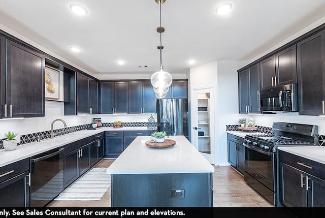 kitchen featuring sink, light hardwood / wood-style flooring, hanging light fixtures, a kitchen island, and black appliances