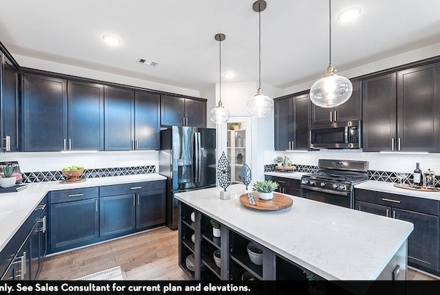 kitchen with decorative backsplash, hanging light fixtures, a center island, light hardwood / wood-style floors, and stainless steel appliances