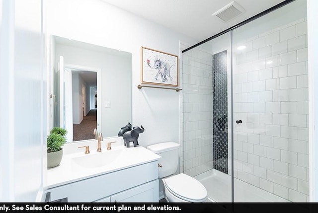 bathroom with a tile shower, vanity, and toilet