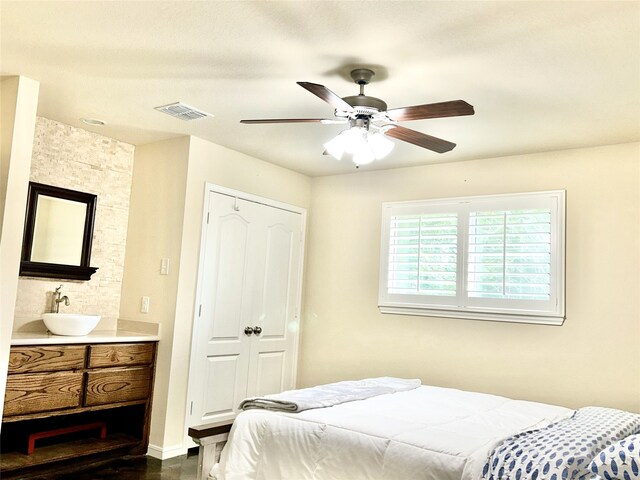 bedroom with dark hardwood / wood-style floors, a closet, sink, and ceiling fan