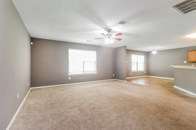 carpeted spare room featuring a textured ceiling and ceiling fan