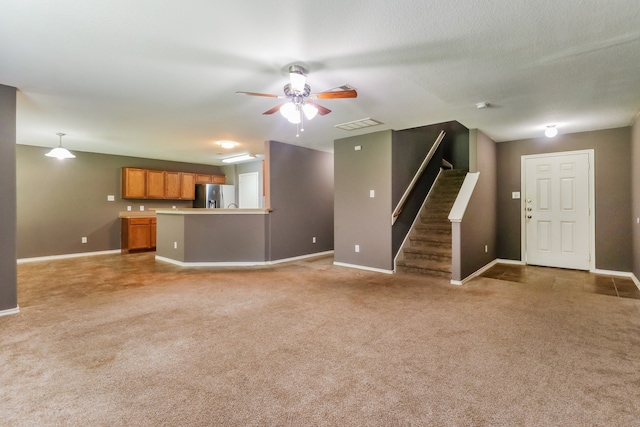 unfurnished living room featuring a textured ceiling, light colored carpet, and ceiling fan