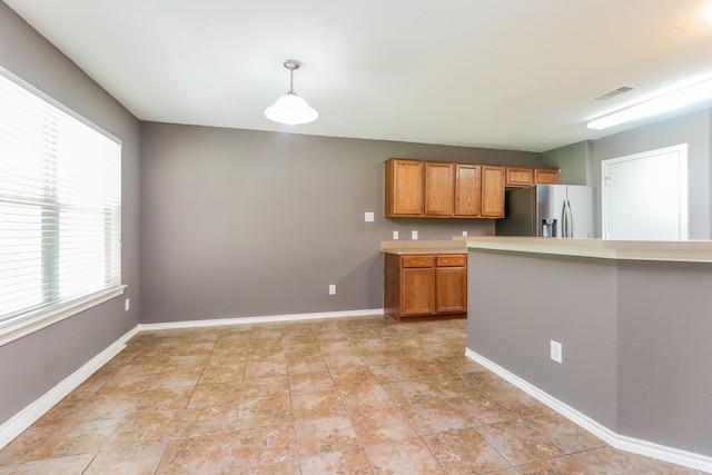 kitchen with light tile patterned flooring, decorative light fixtures, a wealth of natural light, and stainless steel fridge with ice dispenser