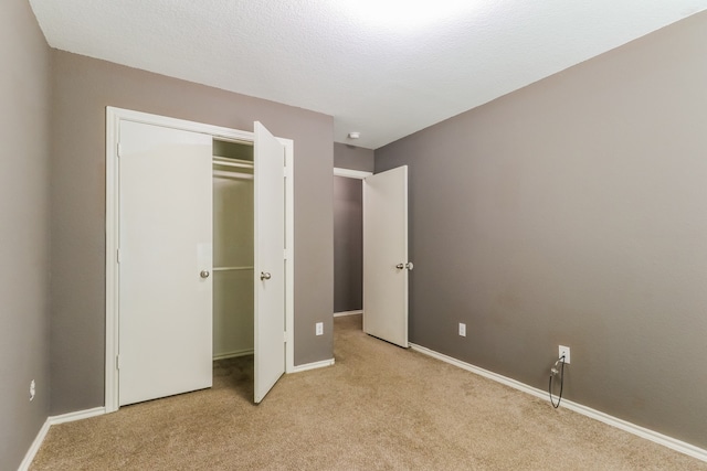 unfurnished bedroom featuring light carpet and a closet