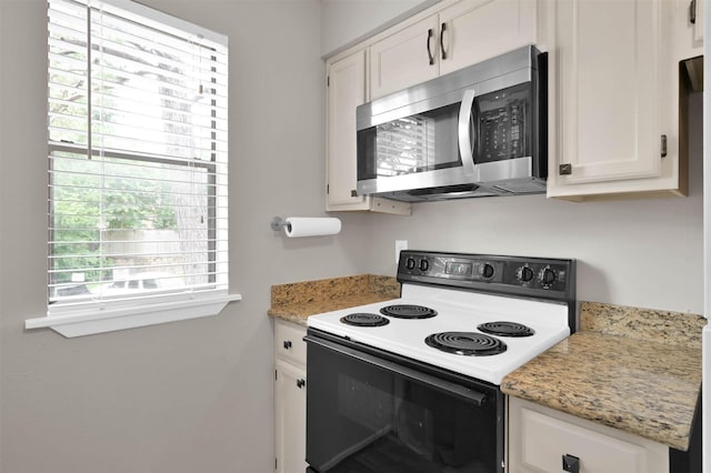 kitchen with white cabinetry, electric range oven, and light stone countertops