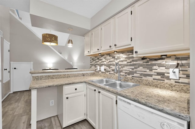 kitchen featuring white dishwasher, sink, decorative light fixtures, and white cabinets