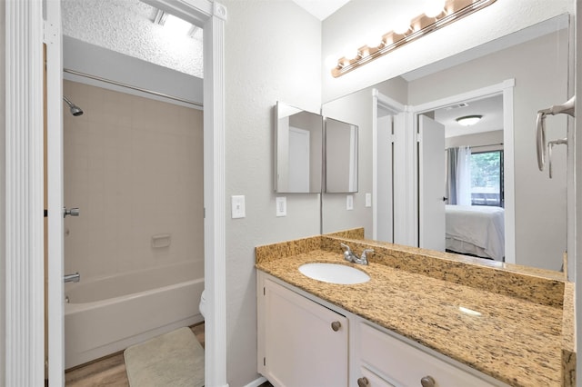 full bathroom with vanity, wood-type flooring, a textured ceiling, tiled shower / bath, and toilet