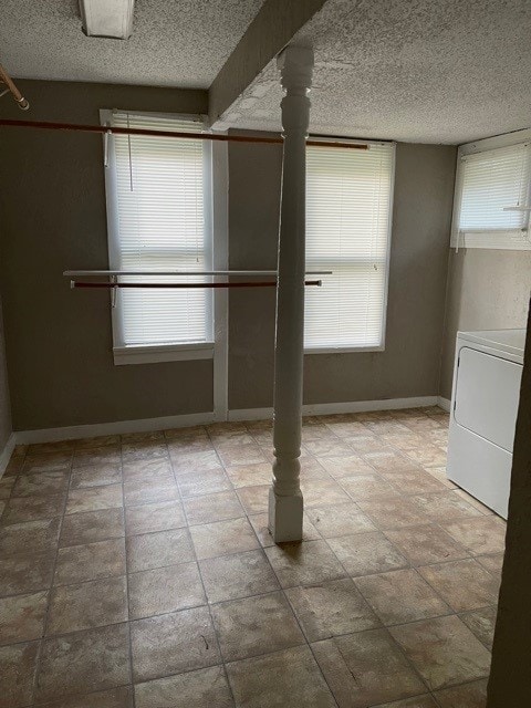 unfurnished room featuring washer / clothes dryer, tile patterned flooring, a healthy amount of sunlight, and a textured ceiling