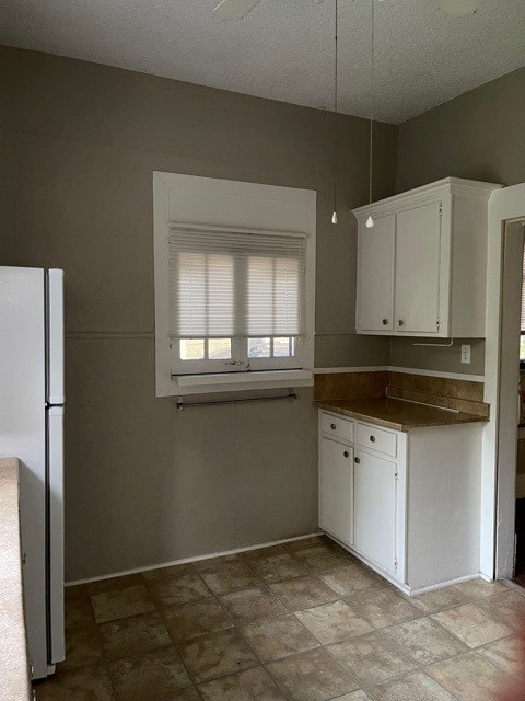 kitchen with light tile patterned flooring, white cabinetry, and stainless steel refrigerator