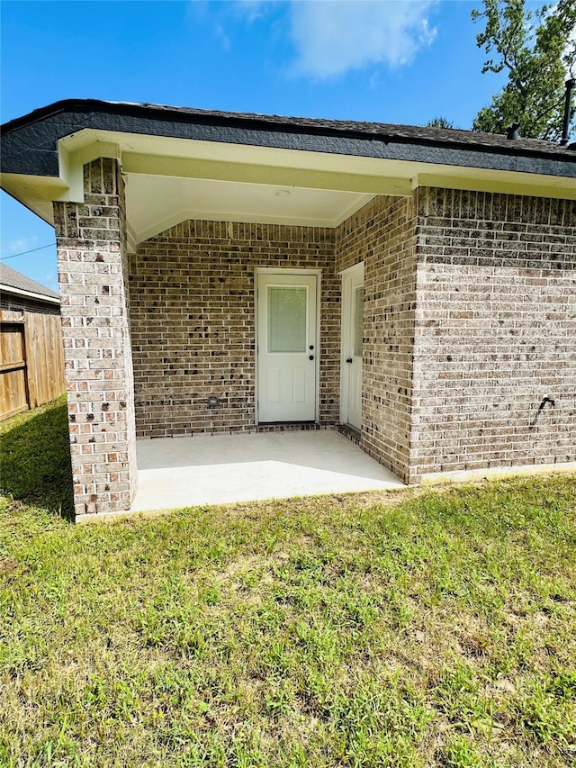 view of exterior entry featuring a patio and a yard