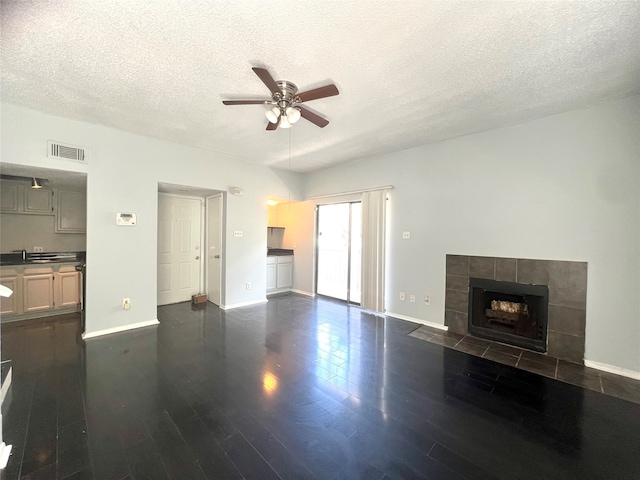 unfurnished living room with a textured ceiling, dark hardwood / wood-style flooring, a fireplace, and ceiling fan