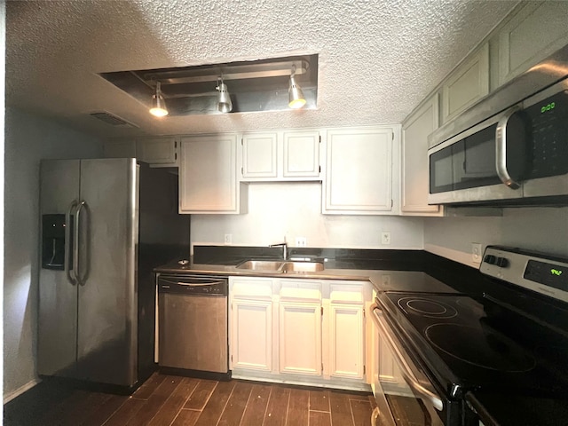 kitchen with dark hardwood / wood-style flooring, rail lighting, sink, appliances with stainless steel finishes, and a textured ceiling