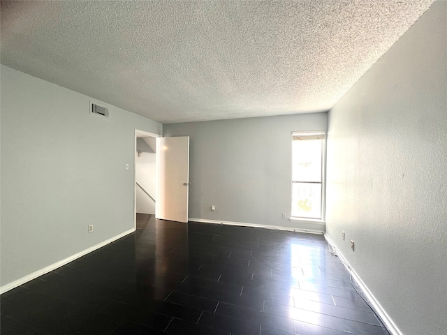 spare room with a textured ceiling and hardwood / wood-style flooring