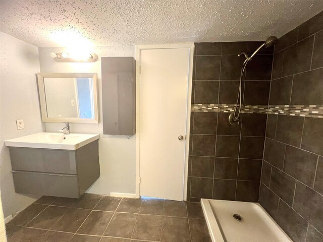 bathroom featuring a tile shower, tile patterned floors, vanity, and a textured ceiling