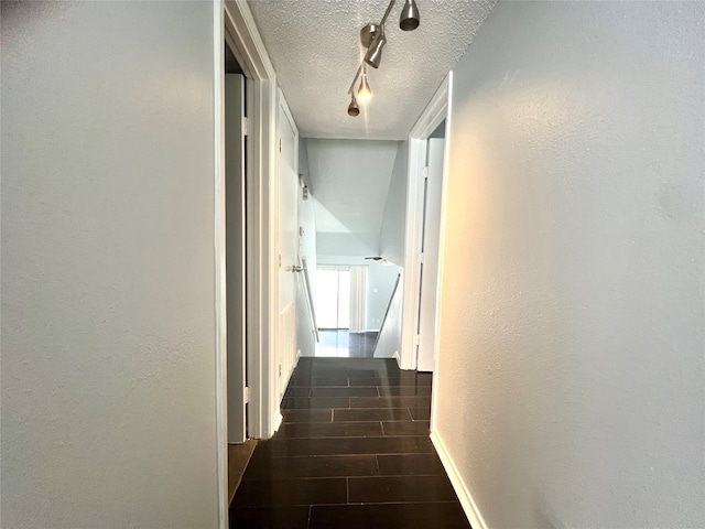 hall featuring a textured ceiling and rail lighting