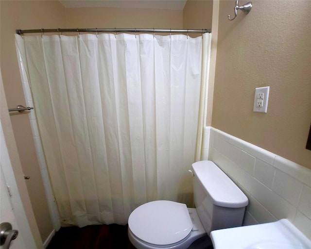 bathroom featuring toilet and tile walls