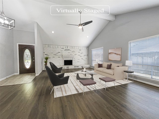 living room with dark hardwood / wood-style floors, ceiling fan with notable chandelier, high vaulted ceiling, a fireplace, and beamed ceiling