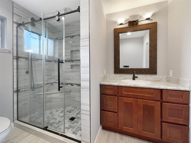 bathroom featuring vanity, a shower with shower door, and toilet