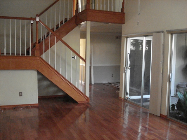 stairs with hardwood / wood-style floors and a high ceiling