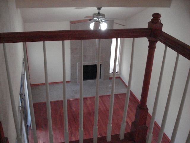 stairs with a tile fireplace and ceiling fan