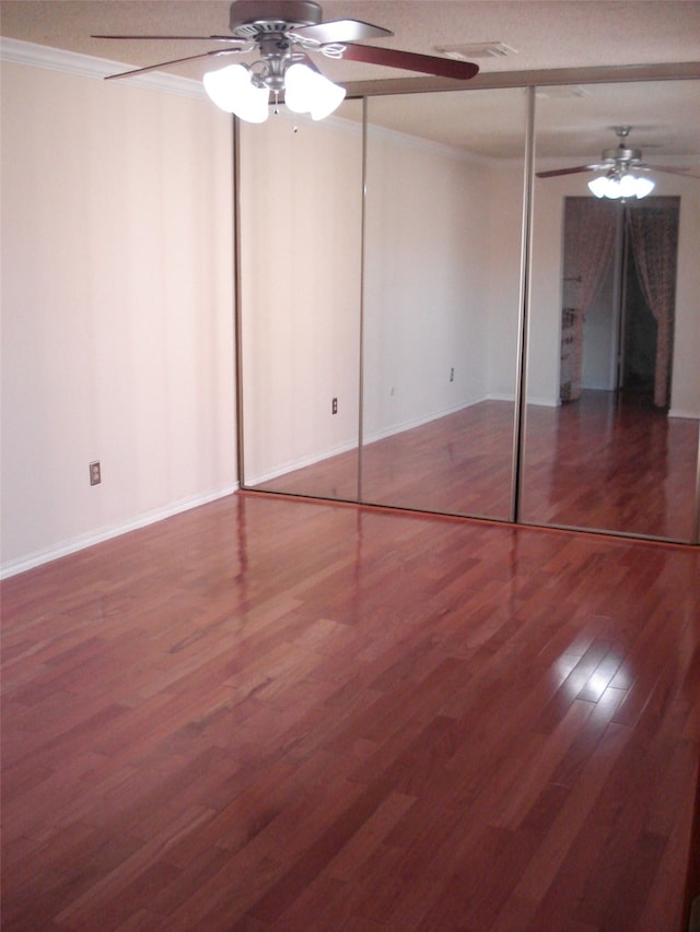 unfurnished bedroom featuring ornamental molding, a closet, hardwood / wood-style flooring, and ceiling fan