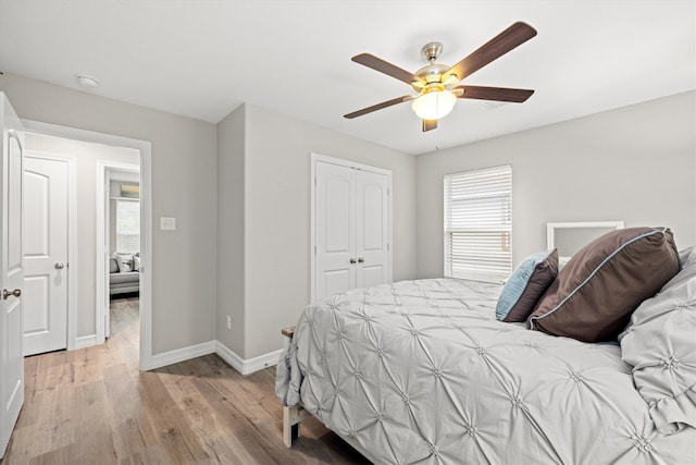 bedroom with a closet, light hardwood / wood-style flooring, multiple windows, and ceiling fan