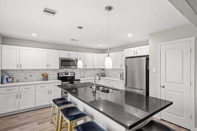 kitchen featuring white cabinetry, stainless steel appliances, sink, light hardwood / wood-style floors, and backsplash