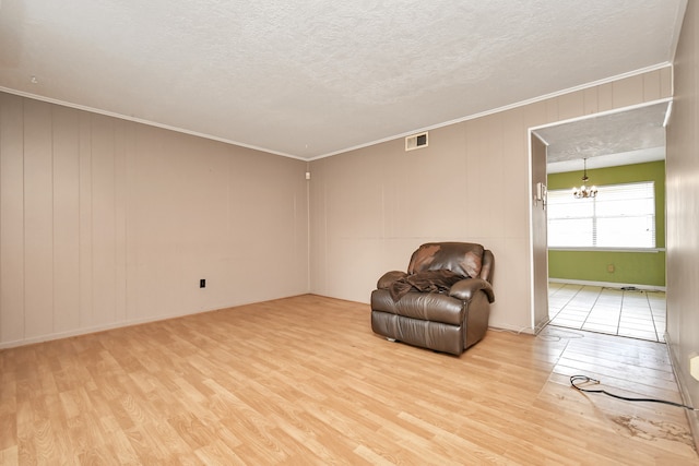 unfurnished room featuring an inviting chandelier, a textured ceiling, and light hardwood / wood-style floors