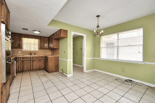 kitchen featuring sink, a textured ceiling, decorative light fixtures, and light tile patterned floors