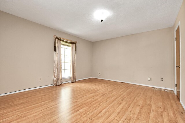 unfurnished room with a textured ceiling and light hardwood / wood-style flooring