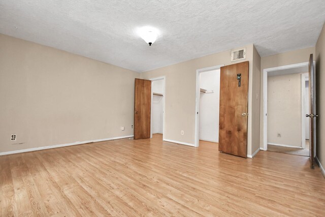 unfurnished bedroom with a closet, a textured ceiling, and light wood-type flooring