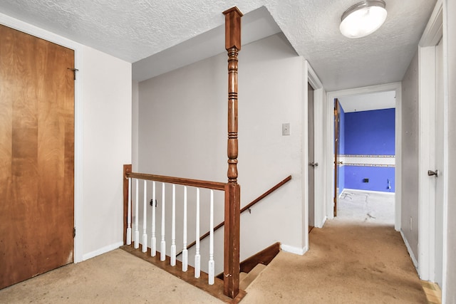 hallway featuring a textured ceiling and light carpet