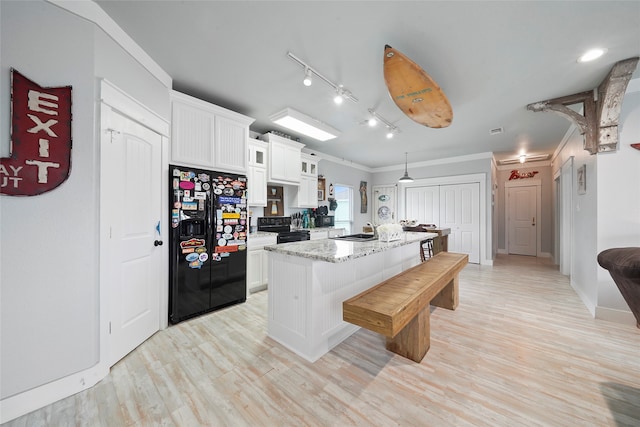 kitchen with white cabinetry, light hardwood / wood-style flooring, rail lighting, black appliances, and light stone countertops