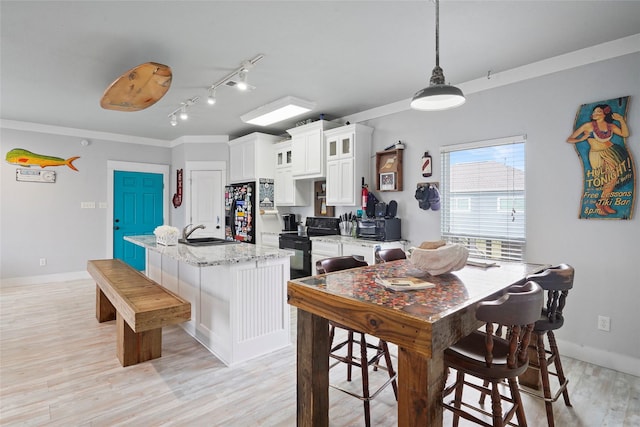 962 Driftwood Dr, Crystal Beach, TX 77650 - kitchen featuring a sink, white cabinets, a center island with sink, light wood-style flooring, and black appliances