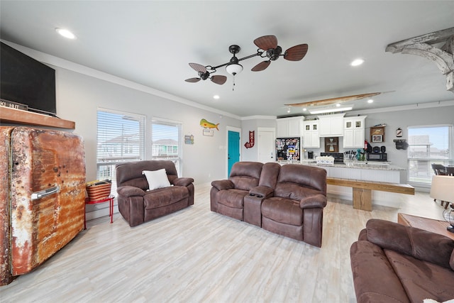 living room featuring a healthy amount of sunlight, ceiling fan, light wood-type flooring, and crown molding