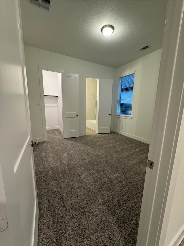 unfurnished bedroom with a textured ceiling and dark carpet