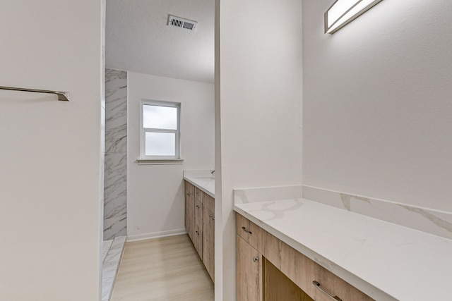 bathroom featuring hardwood / wood-style floors, a textured ceiling, and vanity